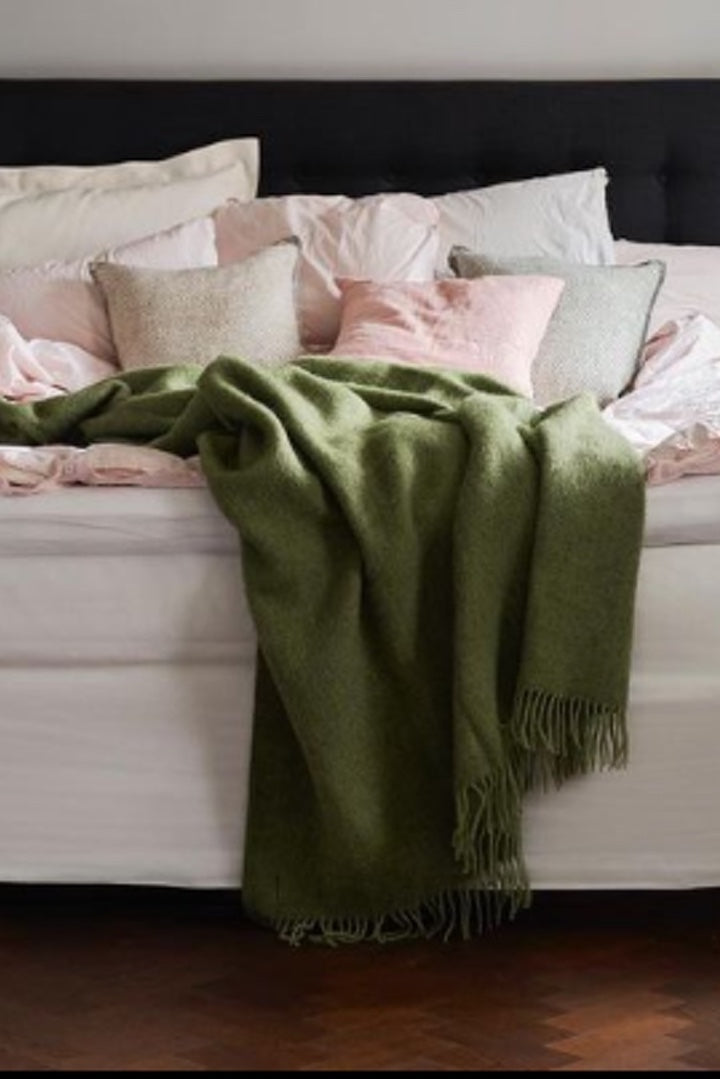 Green Cosy Wool Blanket draped on bed