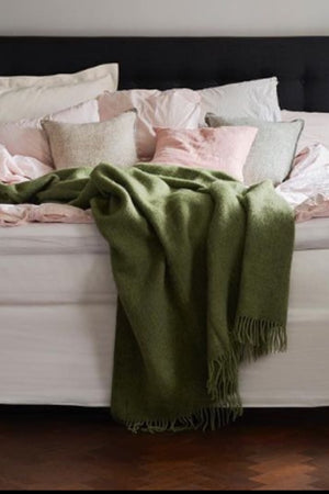 Green Cosy Wool Blanket draped on bed